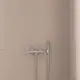 Brausearmatur von Ideal Standard, mit einem Handbrausekopf und flexiblen Schläuchen an einer hellen Wand montiert.